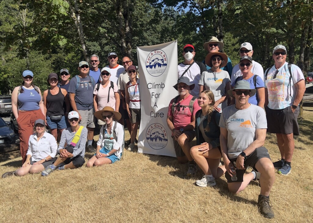 group of men and women pose for photo with a climb for a cure banner